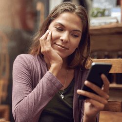 Woman smiling as she reads a message on her phone